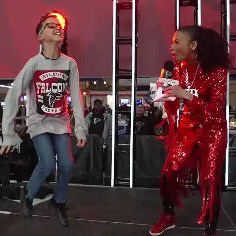 Looping clip: Chelsea in red sequins leading a young fan in an on-stage dance-off