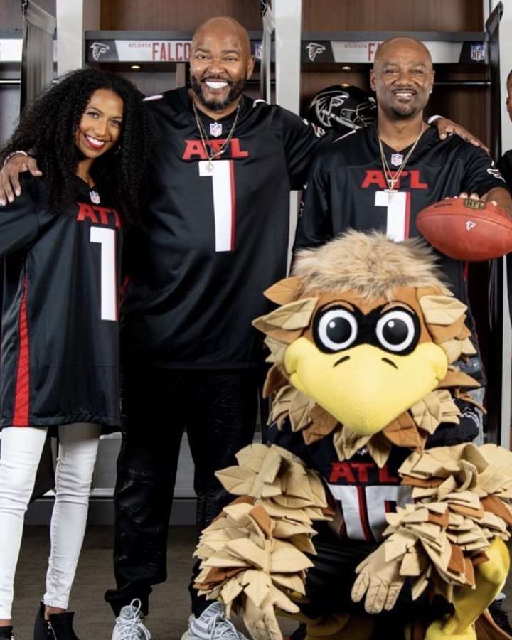 Chelsea in a Falcons jersey in the team locker room with the Falcons mascot