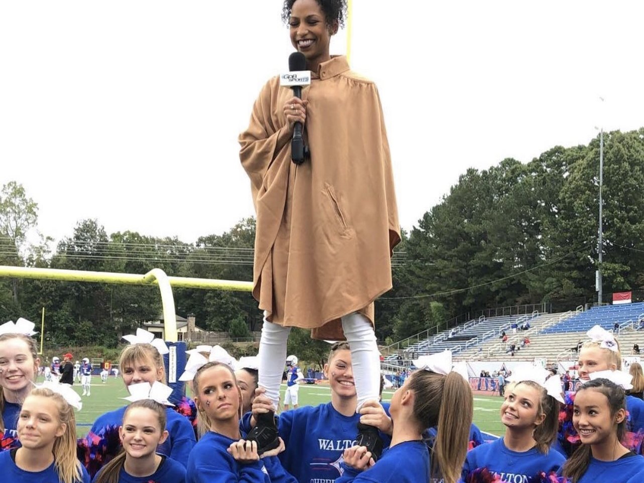 Chelsea lifted high by a high school cheer squad on the sidelines with a mic
